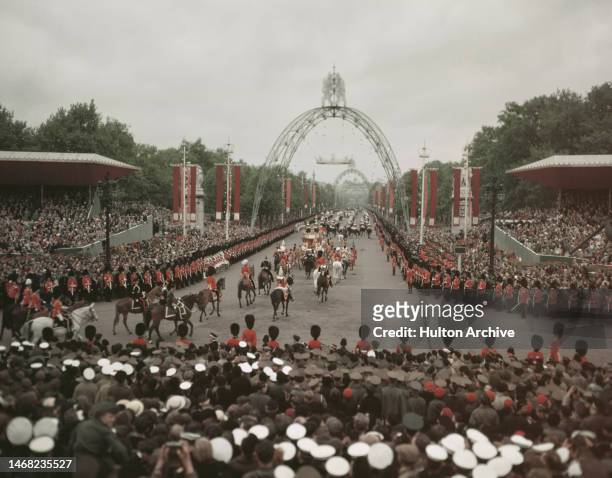 British sailors, soldiers and crowds line the route of Queen Elizabeth's coronation procession, the Mall, London, 2nd June, 1953. Coronation arches...