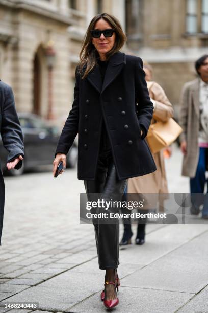 Guest wears black sunglasses, a black t-shirt, a black buttoned jacket, black shiny leather large pants, black tights, red shiny leather pointed...