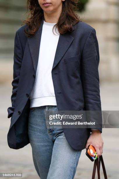 Guest wears a white sweater, a black blazer jacket, blue faded denim pants , outside Emilia Wickstead, during London Fashion Week February 2023 on...