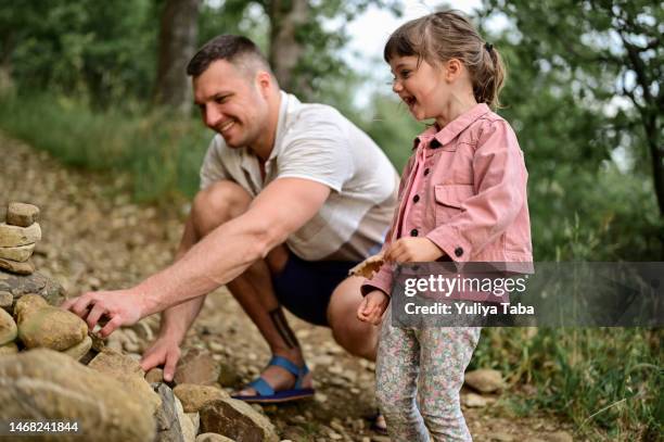 happy family time lifestyle outdoors. laughing daughter with her daddy plays in nature.family builds stone stacks. - the two towers stock pictures, royalty-free photos & images