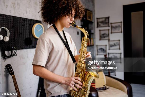 un jeune homme joue du saxophone - saxophone photos et images de collection