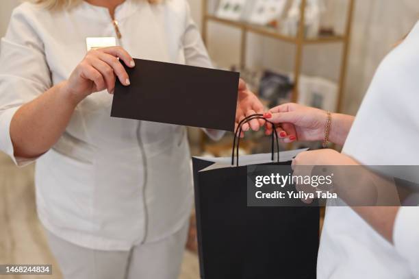 frau, die schönheitsprodukte und geburtstagsurkunde in einem schönheitssalon kauft. - gutschein stock-fotos und bilder