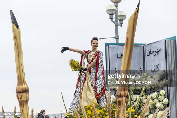 Jeune femme avec un bouquet de mimosa sur un char fleuri lors du défilé des 150 ans du carnaval de Nice le 18 février 2023.