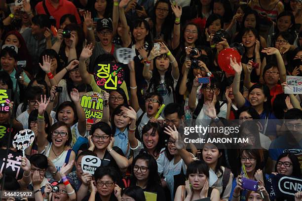 Pop fans, holding signs with the names of their favourite K-Pop groups, cheer and shout outside the venue of the K-Pop Festival Music Bank concert...