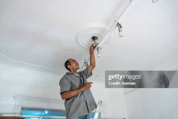 electrician repairs the light fixtures - installing ceiling light fixture stock pictures, royalty-free photos & images