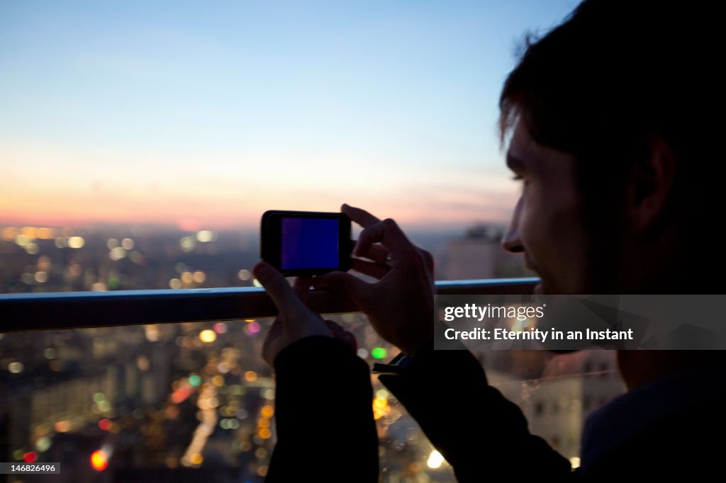 Businessman taking photo of city with camera phone