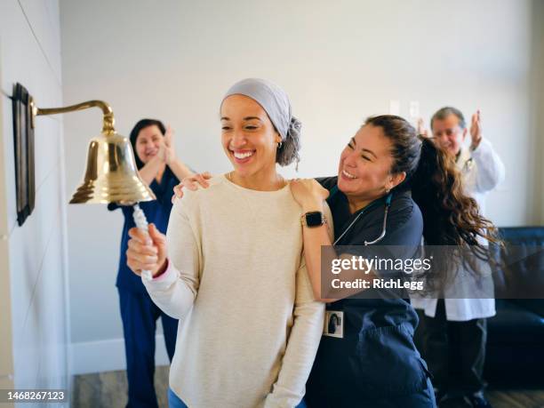 adult woman chemotherapy patient finishing treatment with a ceremonial bell ring - ringing bell stock pictures, royalty-free photos & images