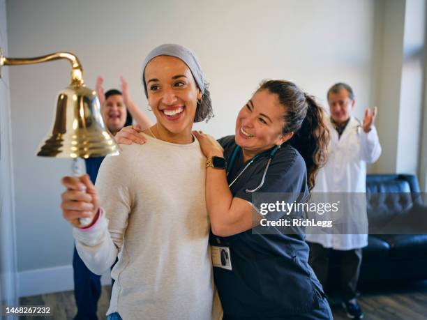 femme adulte patiente en chimiothérapie terminant son traitement avec un anneau de cloche cérémoniel - symbole sonne photos et images de collection