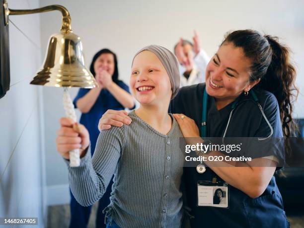 paciente de quimioterapia infantil que termina el tratamiento con un toque de campana ceremonial - campana fotografías e imágenes de stock