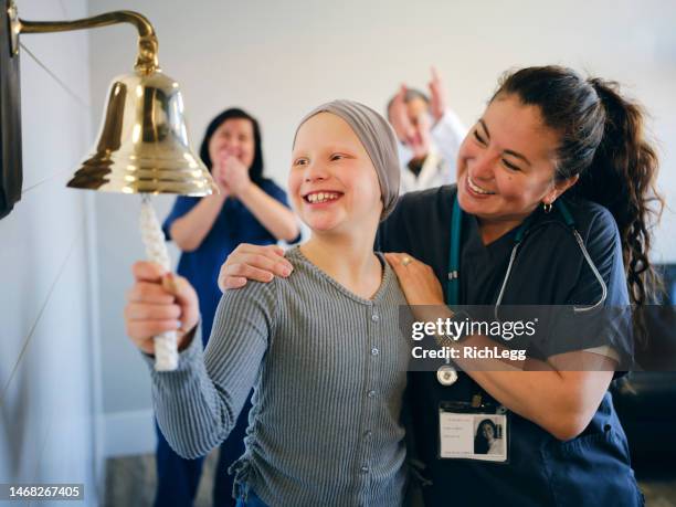 un patient en chimiothérapie pour enfants termine son traitement avec un anneau de cloche cérémoniel - symbole sonne photos et images de collection