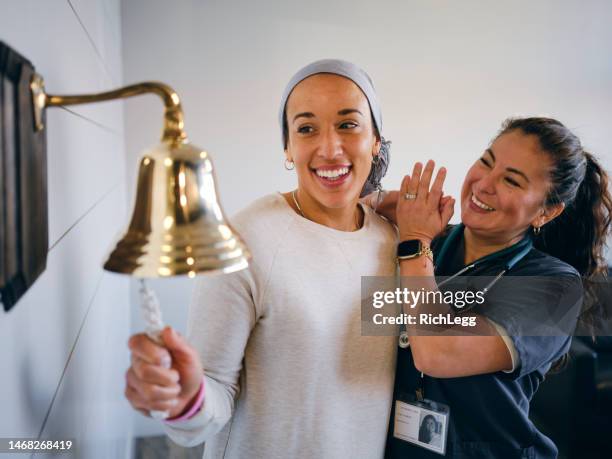 adult woman chemotherapy patient finishing treatment with a ceremonial bell ring - ringing bell stock pictures, royalty-free photos & images