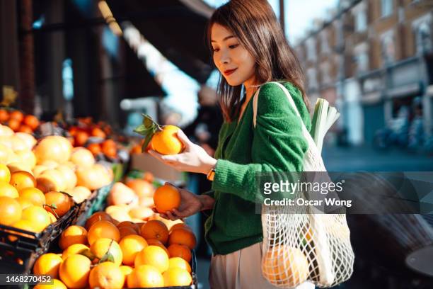 young asian woman shopping fresh fruits and vegetables at organic food market - frau kauft lebensmittel stock-fotos und bilder