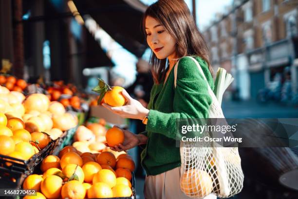 young asian woman shopping fresh fruits and vegetables at organic food market - mercato di prodotti agricoli foto e immagini stock