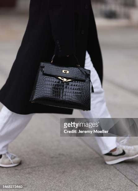 Sarah Harris seen wearing a black Hermes croco Kelly bag, white pants, a black coat and sneakers before the Emilia Wickstead show during London...