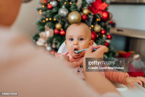 baby girl sitting on high chair while eating a meal - christmas breakfast stock pictures, royalty-free photos & images
