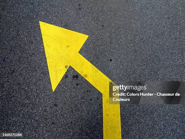 a yellow arrow painted on the gray tarmac of a street in geneva - links platz stock-fotos und bilder