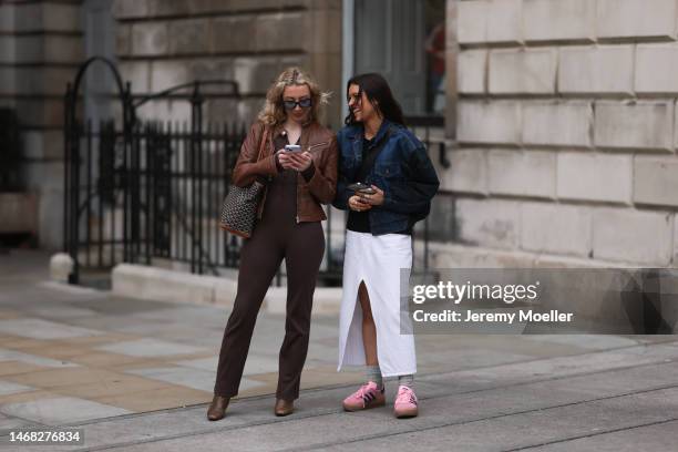 Fashion week guest seen wearing a white skirt, grey socks by Nike, Adidas Gazelle pink and navy blue sneakers and a jeans jacket and another fashion...