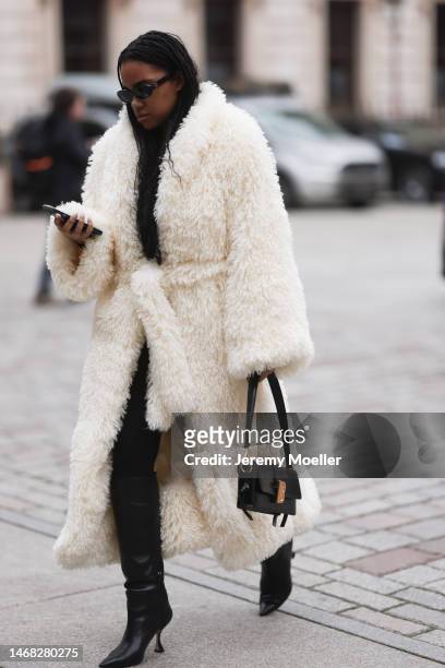 Fashion week guest seen wearing a fluffy white long coat, black pants, black boots, black shades and a black leather bag before the Emilia Wickstead...