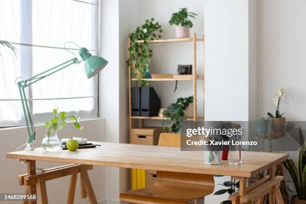 empty bright cozy home office workplace with large wooden table, office supplies, desk chair and plants. - empty desk stock pictures, royalty-free photos & images