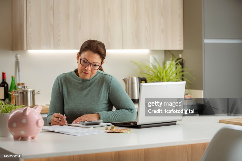 Home finances: woman analyzing bills while sitting in kitchen