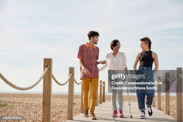 happy friends walking on sunny beach boardwalk - indian lesbian stock pictures, royalty-free photos & images