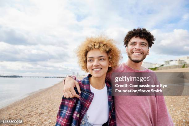 smiling couple on sunny beach - urlaub frau strand sonne blond kurze haare stock-fotos und bilder