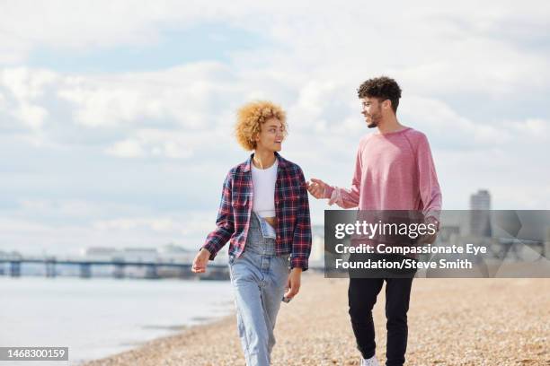 smiling couple walking on sunny beach - pink pants stockfoto's en -beelden