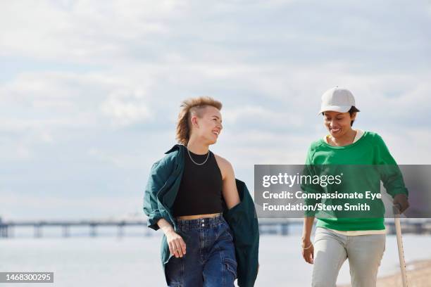 friends walking on sunny beach - spazierstock stock-fotos und bilder