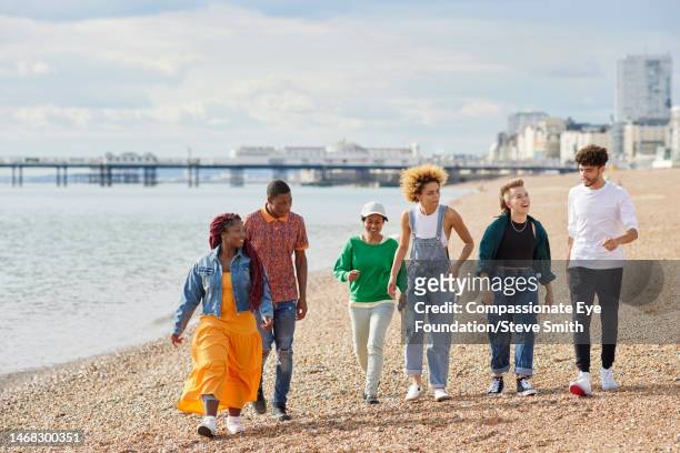 happy friends walking on sunny beach - asian woman black shirt stock pictures, royalty-free photos & images