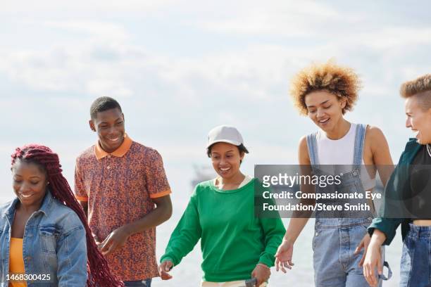 happy friends walking on beach - brighton england stock pictures, royalty-free photos & images
