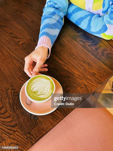 overhead view of a woman drinking a matcha latte - matcha tea stock pictures, royalty-free photos & images