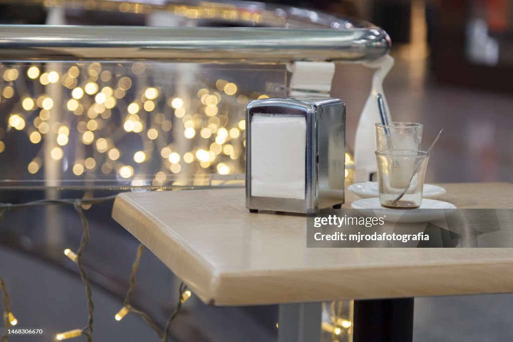 Close-up of two empty glasses and a napkin dispenser on a table in a cafe