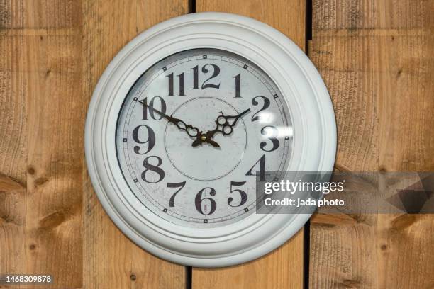 white clock with numbers hanging on a wooden wall - horloge murale photos et images de collection