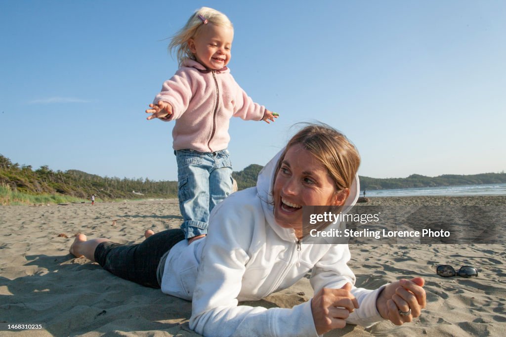 Beach play for mother and daughter baby girl at Cox bay, Tofino, British Columbia