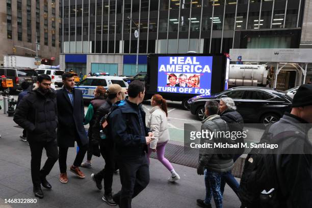People pass by a video truck as members of Rise and Resist participate in their weekly "Truth Tuesday" protest at News Corp headquarters on February...