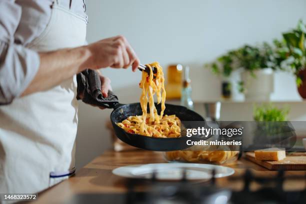 nahaufnahme foto von männerhänden, die nudeln mit frischem gemüse servieren - one pot pasta stock-fotos und bilder