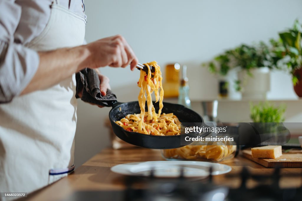 Foto ravvicinata delle mani dell'uomo che servono la pasta con verdure fresche