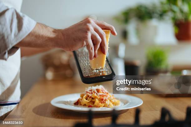 foto de cerca de las manos del hombre rallando queso en pasta con verduras frescas - parmesano fotografías e imágenes de stock