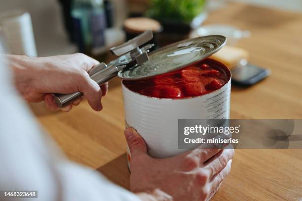 nahaufnahme foto von männerhänden öffnet deckel von tomatenpüree in dosen - blechdose stock-fotos und bilder