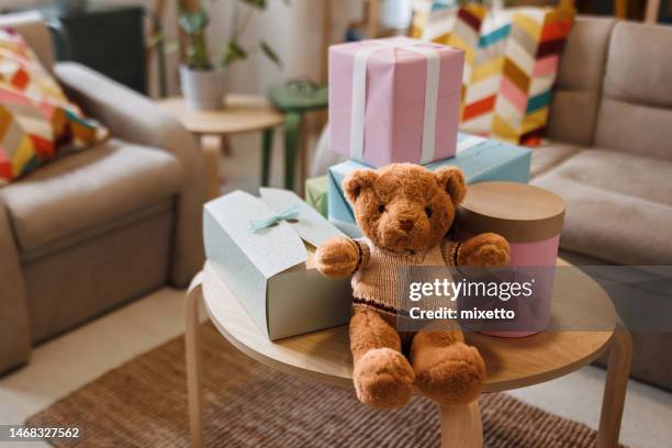 teddy bear with gifts arranged on coffee table for baby shower party with no people - babyshower stockfoto's en -beelden