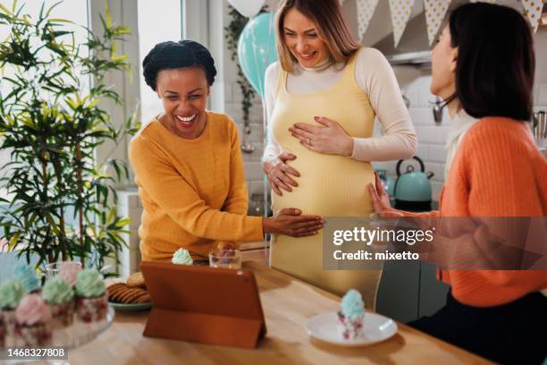 female friends having video call from kitchen while having baby shower party - baby shower party stock pictures, royalty-free photos & images