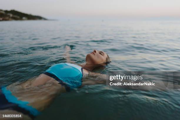 frau im mittleren erwachsenenalter, die im meer schwimmt - auf dem wasser treiben stock-fotos und bilder