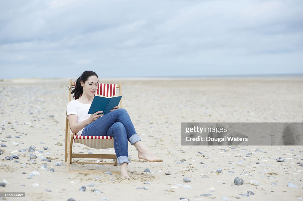 Woman  sitting at beach reading book.