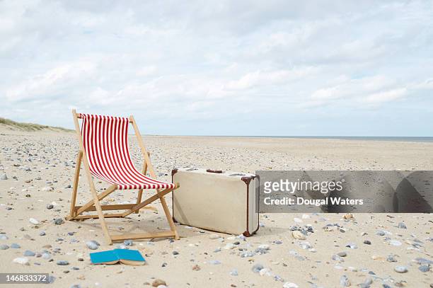 deck chair with suitcase and book at beach. - deckchair stock pictures, royalty-free photos & images