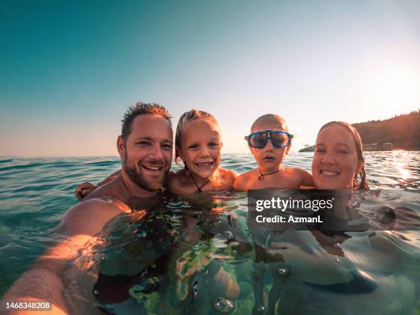 loving father and mother with two kids taking a selfie in the water - mother and child in water at beach stock pictures, royalty-free photos & images