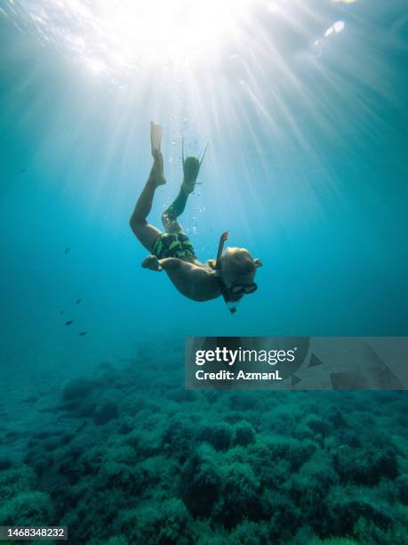 niño explorador nadando en el océano mientras mira rocas - snorkeling fotografías e imágenes de stock