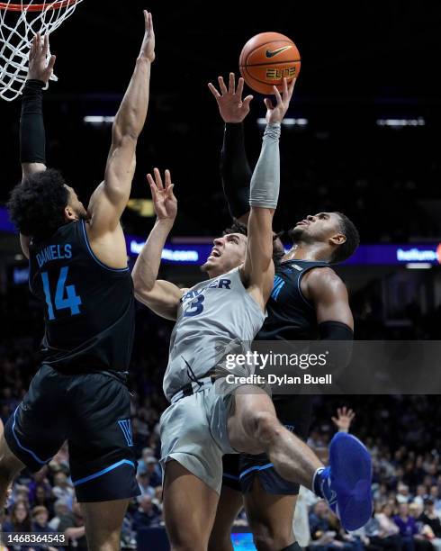 Colby Jones of the Xavier Musketeers attempts a shot while being guarded by Caleb Daniels and Eric Dixon of the Villanova Wildcats in the first half...