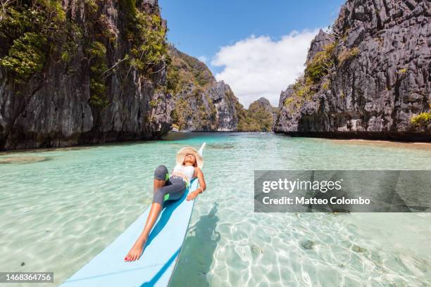 asian woman lying down on boat prow, el nido - palawan stock pictures, royalty-free photos & images