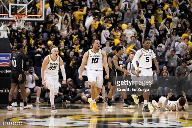 Noah Carter, Nick Honor and D'Moi Hodge of the Missouri Tigers celebrate their 66-64 overtime win over the Mississippi State Bulldogs in the first...