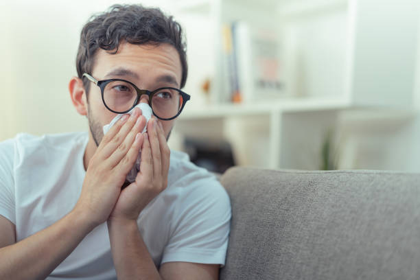 guy with a cold, in his apartment living room - liberal weak stock pictures, royalty-free photos & images